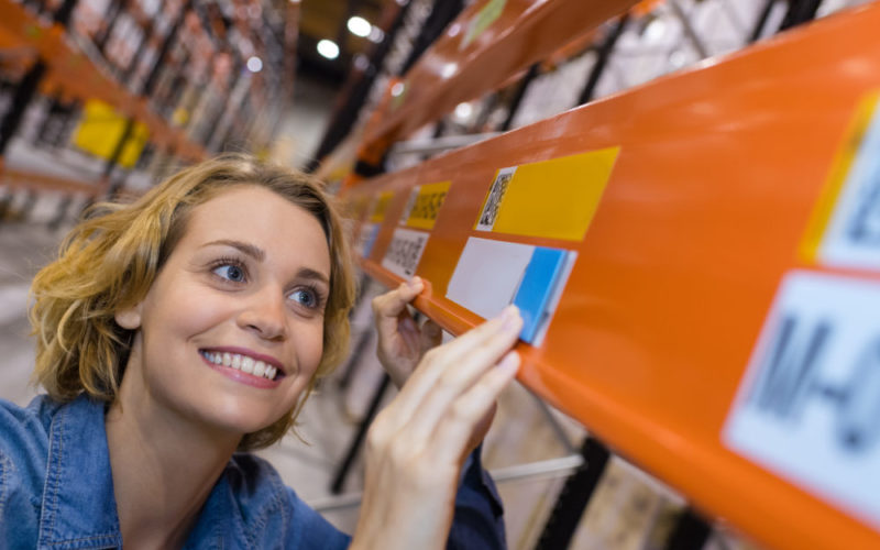 happy warehouse worker putting prices on shelves